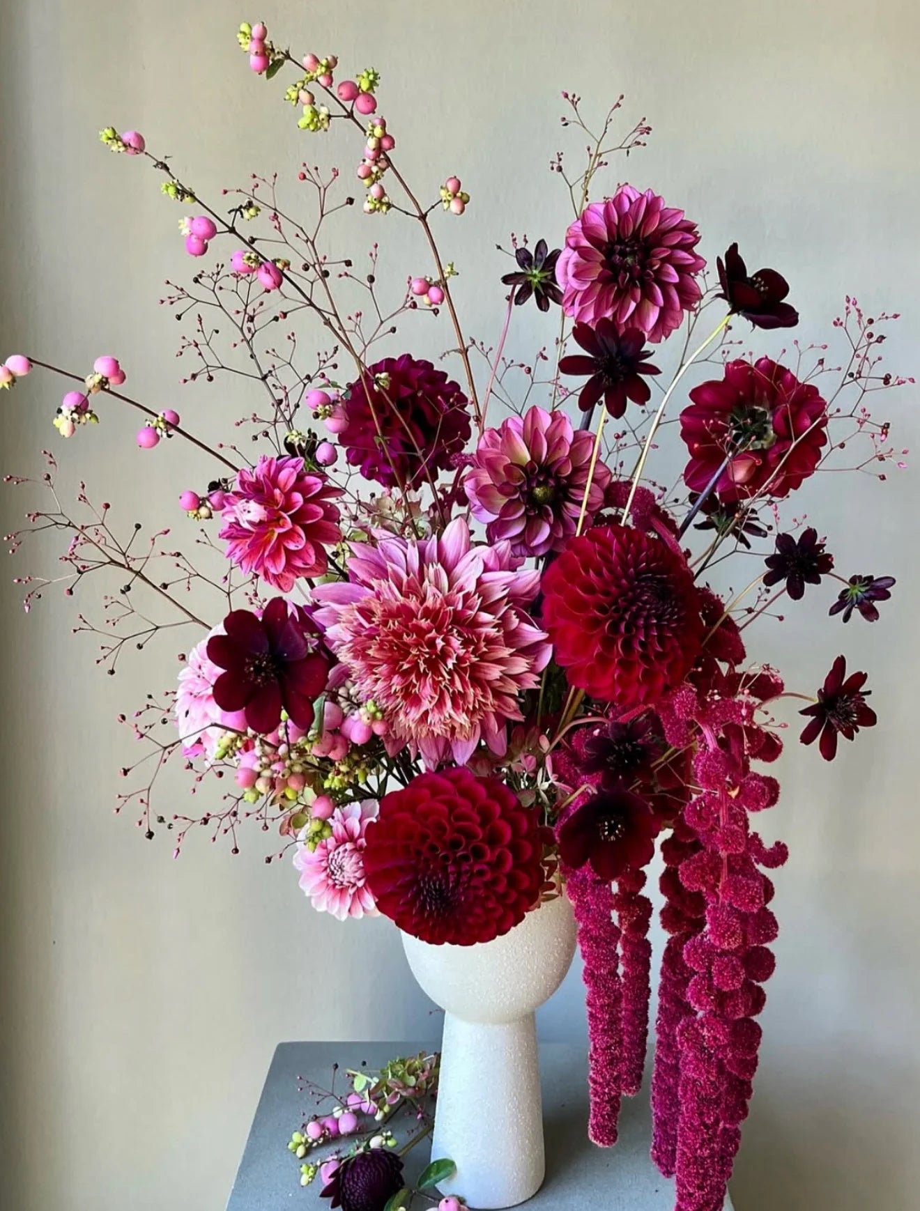 Bouquet of pink and red flowers in a white vase against a neutral background