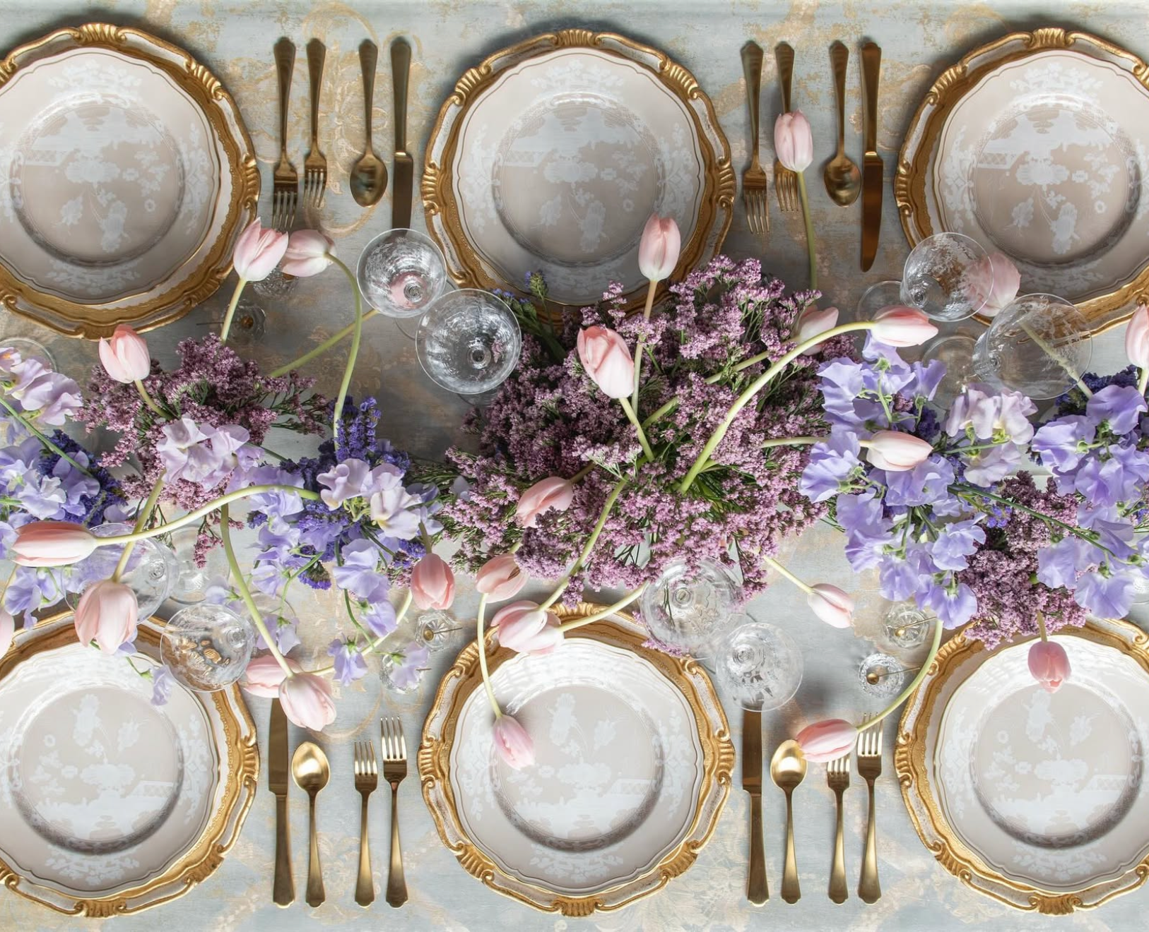 Table setting with plates, flowers, and cutlery on a white background