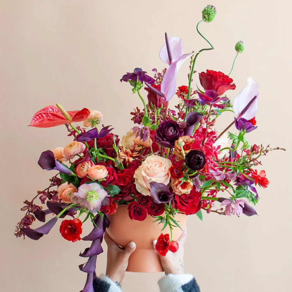 Person wearing a large bouquet of flowers with checkered stockings against a beige background