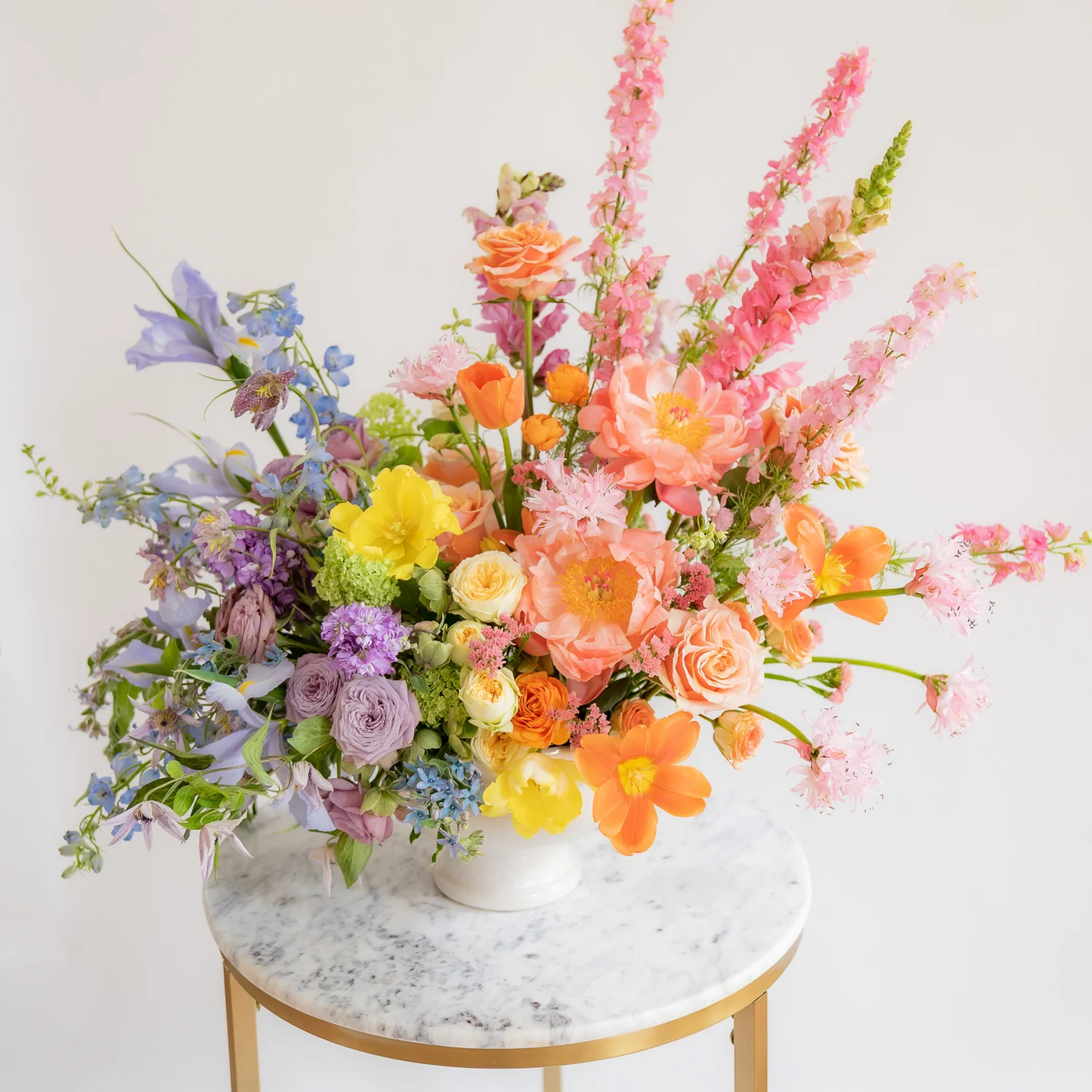Colorful flower arrangement in a vase on a marble table with a white background